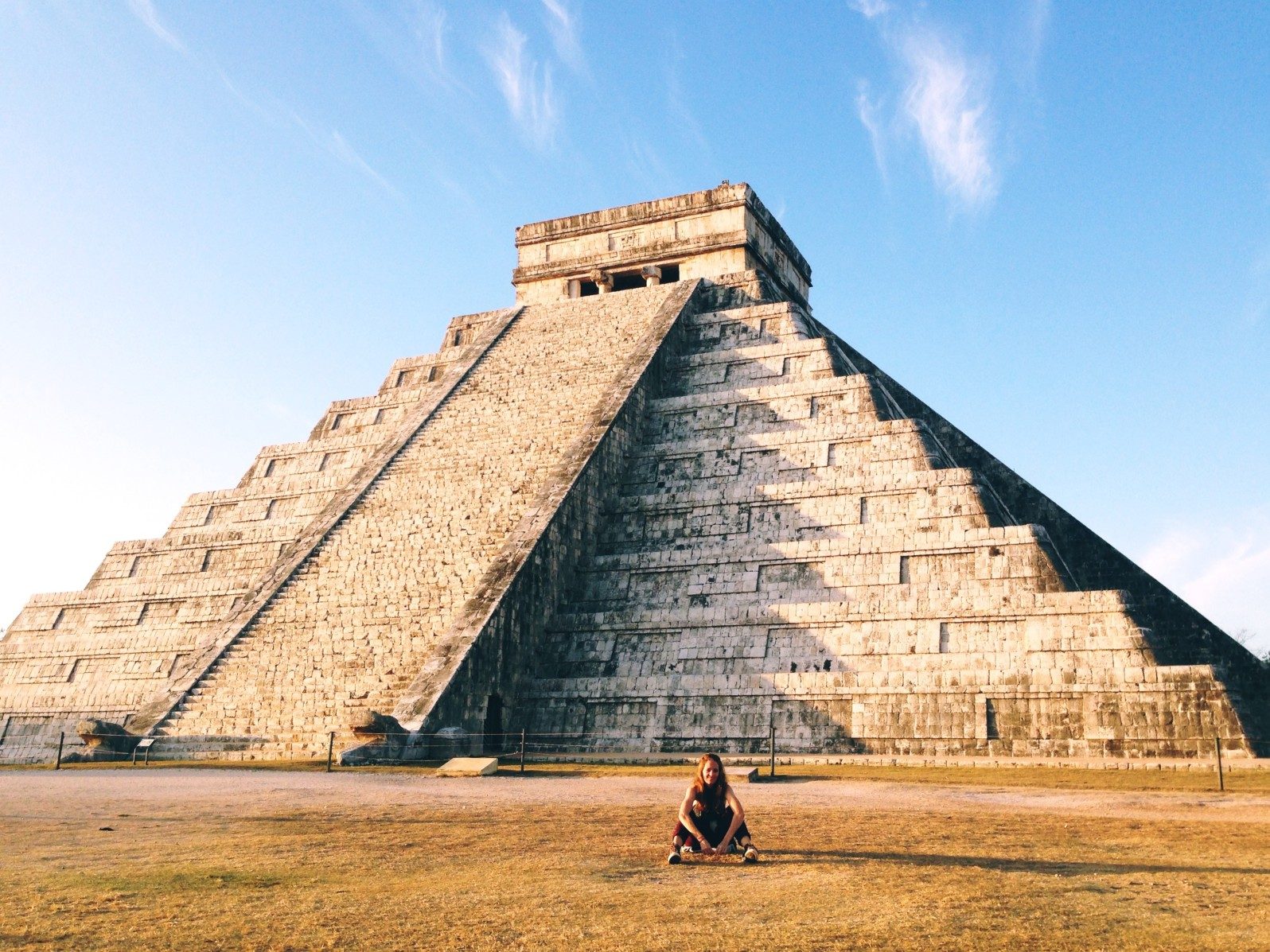 Mujer sentada frente a la pirámide de El Castillo en Chichén Itzá