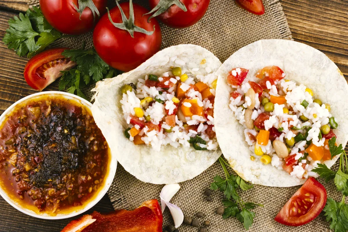 Tacos de arroz con verduras junto a un tazón de salsa y jitomates