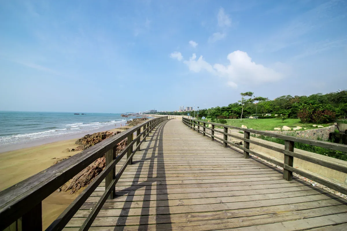 Andador de madera junto a una playa de arena en un día despejado