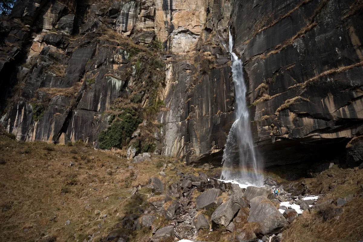 Cascada que cae por una pared de roca oscura sobre piedras