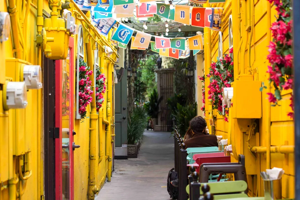 Callejón con fachadas amarillas, flores y banderines de colores