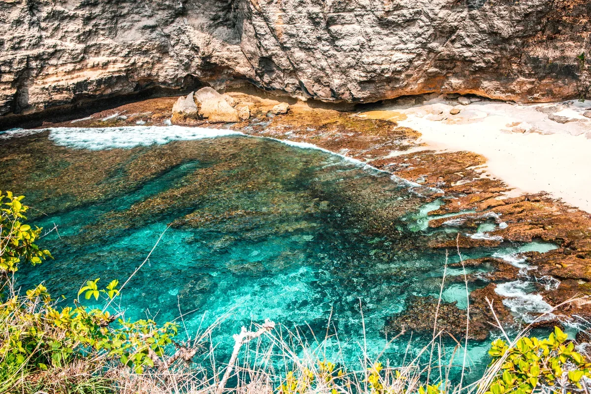 Caleta de agua turquesa entre acantilados rocosos