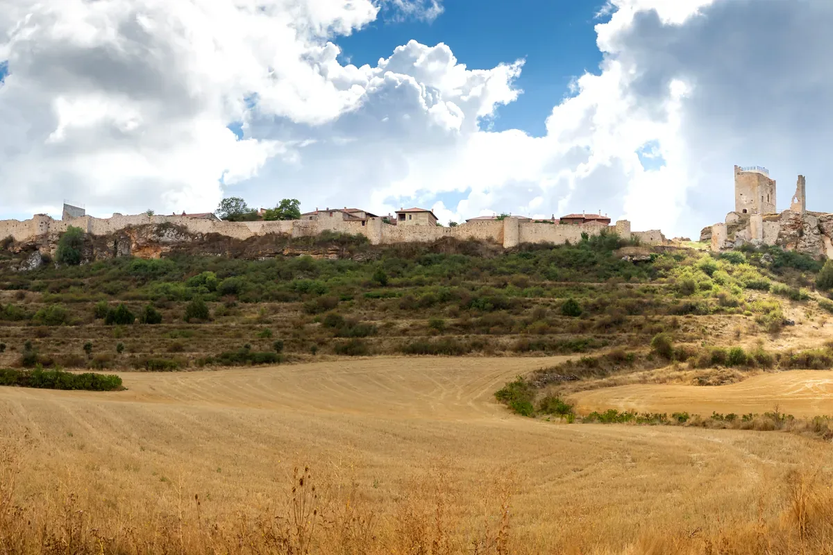 Ruinas de un castillo sobre una colina con campos de trigo