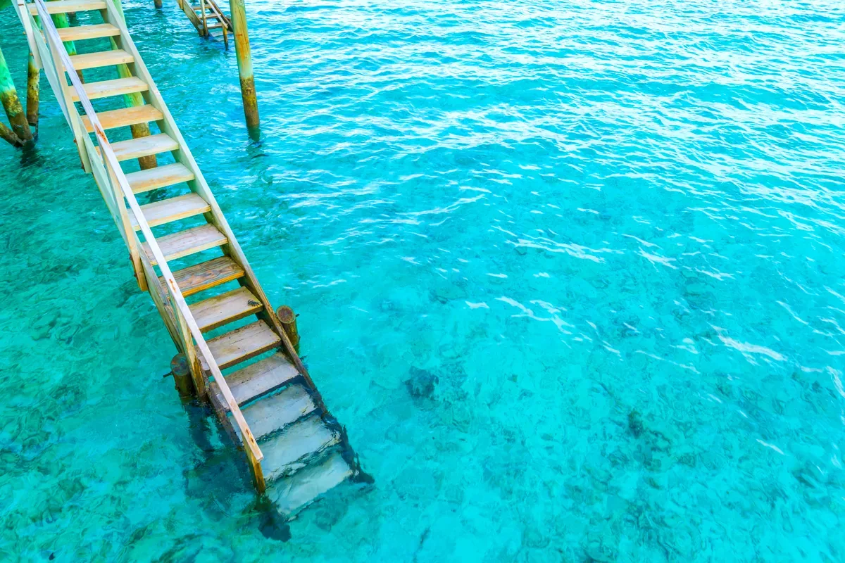 Escalera de madera de un muelle hundida en el mar turquesa