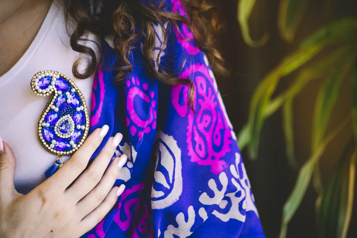 Mujer con un rebozo morado estampado y un broche bordado