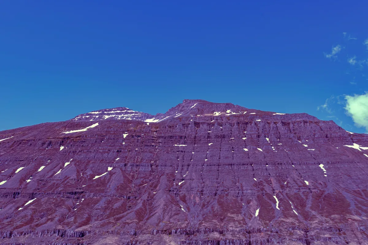 Montaña de cima plana con manchas de nieve en un cielo azul