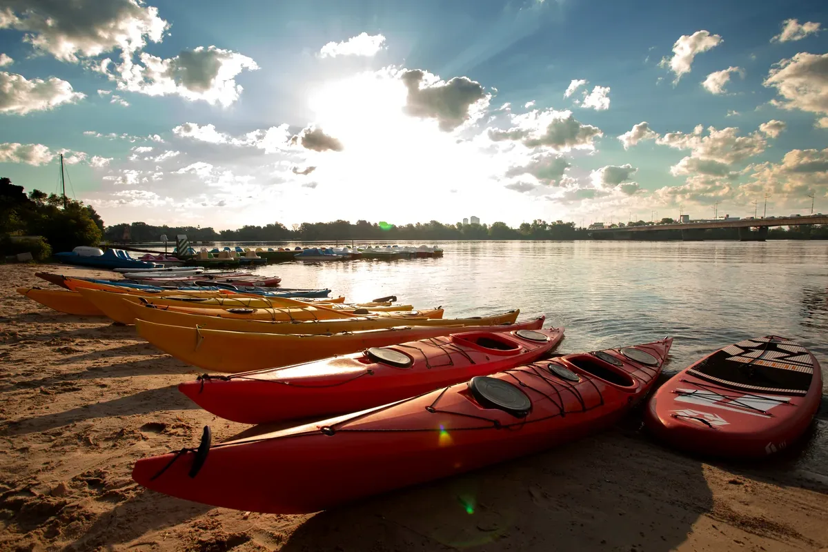 Kayaks rojos y amarillos en la orilla de un lago a contraluz