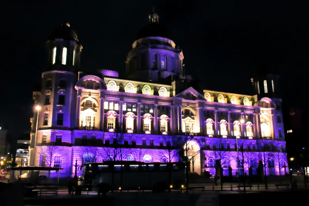 Edificio antiguo con cúpulas iluminado de morado durante la noche