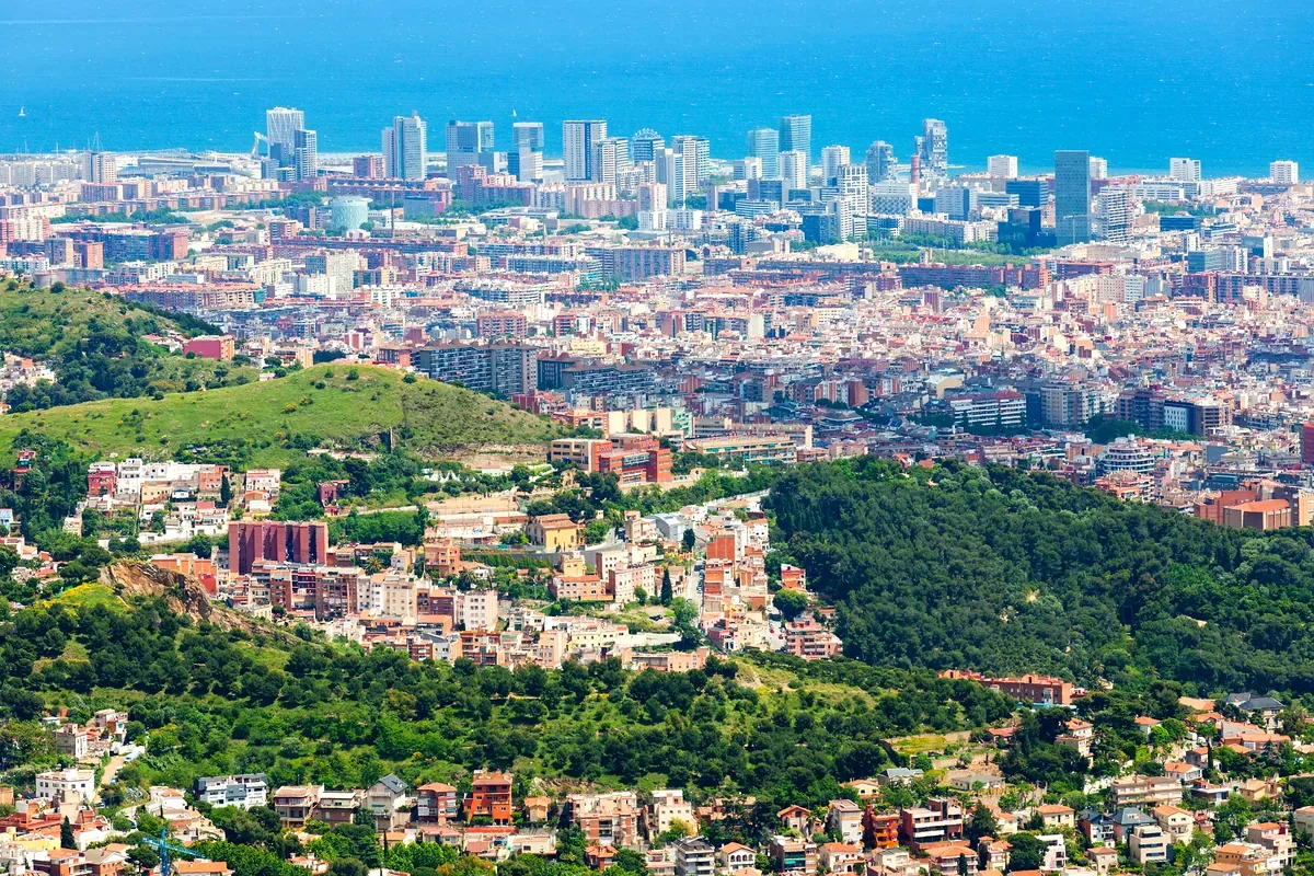 Vista de una ciudad entre cerros verdes con el mar al fondo