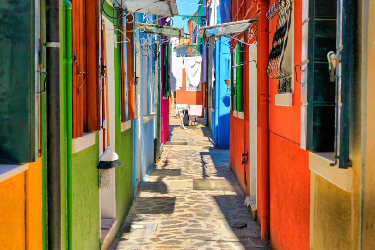 Callejón estrecho entre casas de colores con ropa tendida