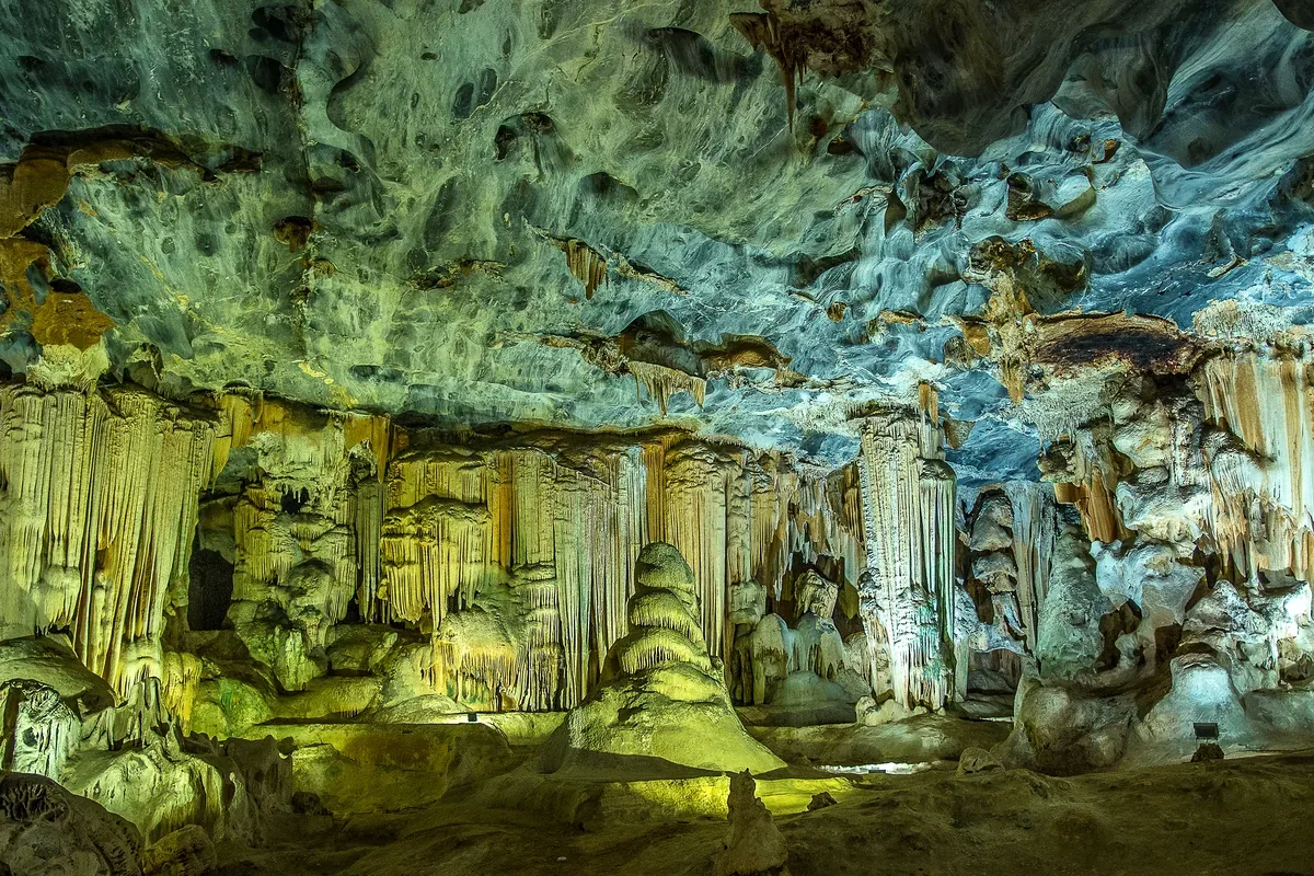 Interior de una cueva con estalactitas y columnas iluminadas