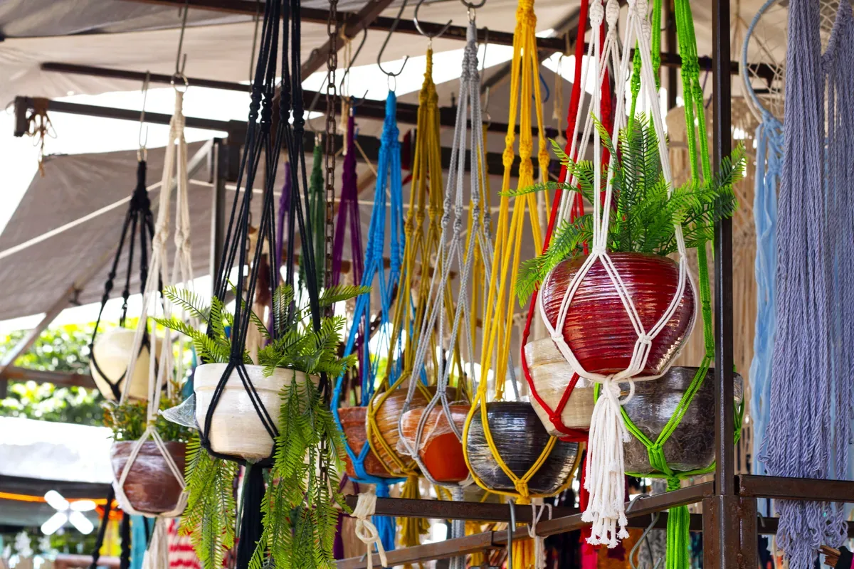 Macetas colgantes tejidas de colores en un puesto de mercado