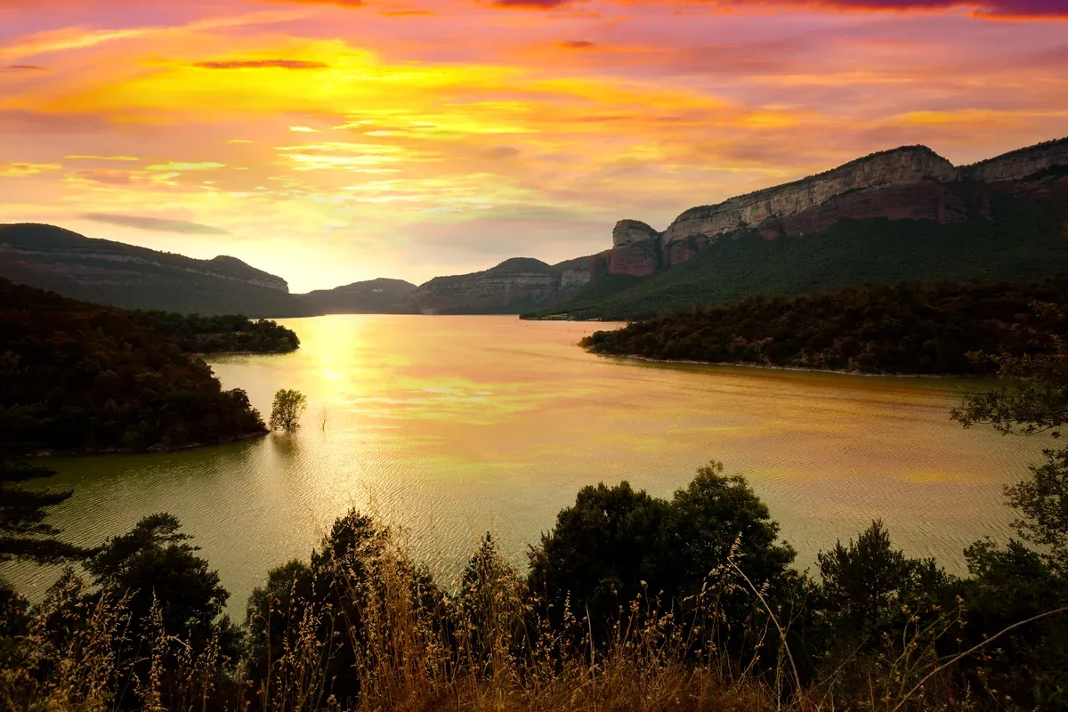 Atardecer sobre un lago entre montañas y acantilados