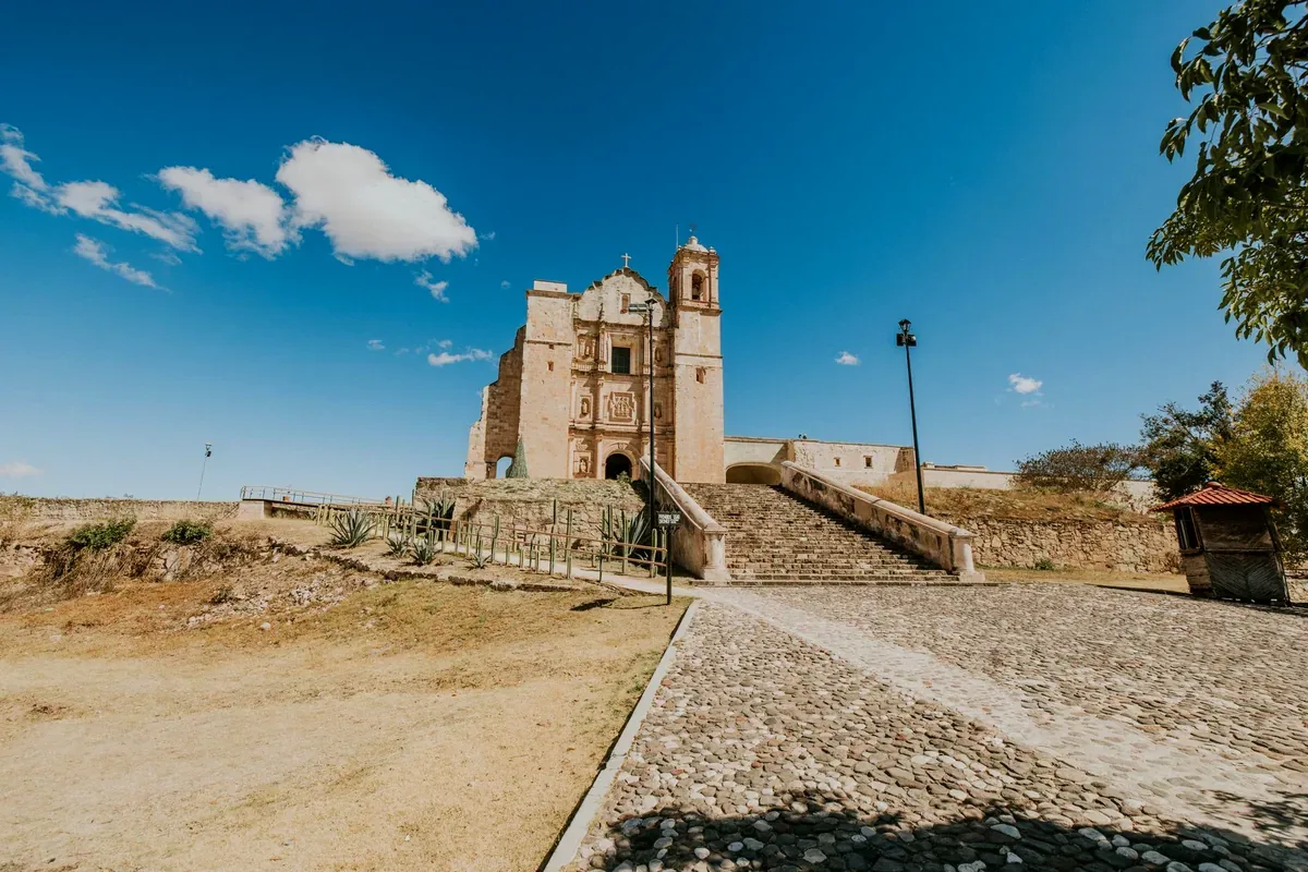 Templo colonial de piedra junto a un camino empedrado bajo un cielo azul