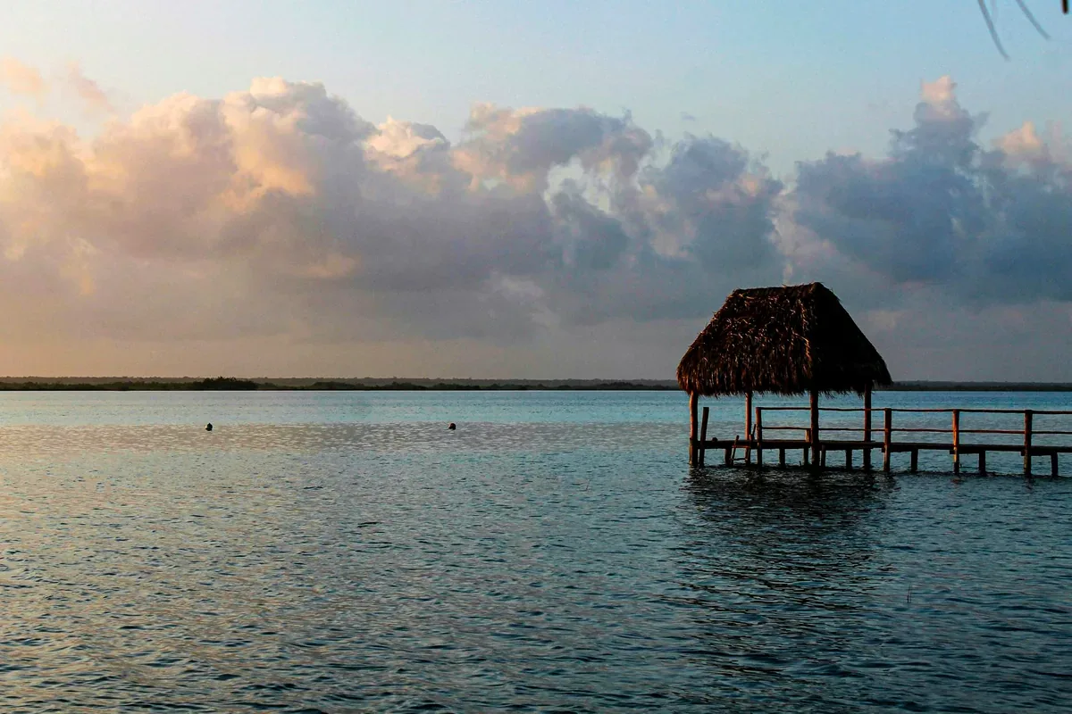 Palapa sobre un muelle en una laguna tranquila al amanecer