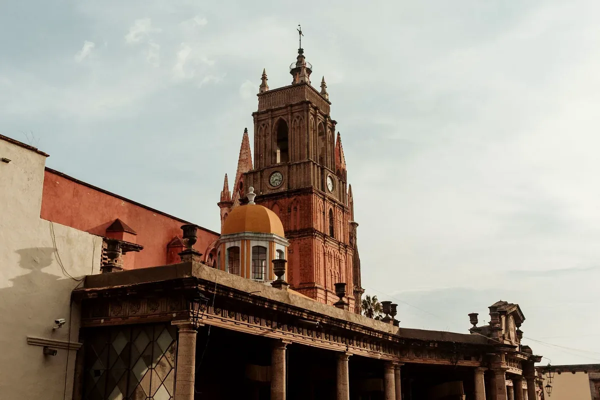 Campanario de cantera rosa con cúpula detrás de un portal antiguo