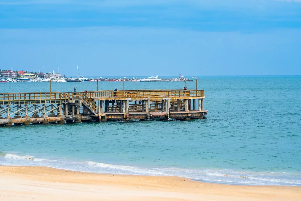 Muelle de madera sobre el mar con una ciudad y una marina al fondo
