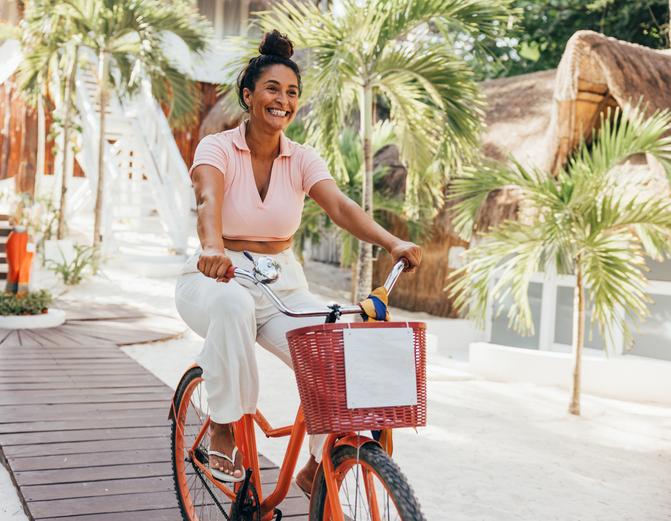 Mujer sonriente que pasea en bicicleta por una calle con palmeras