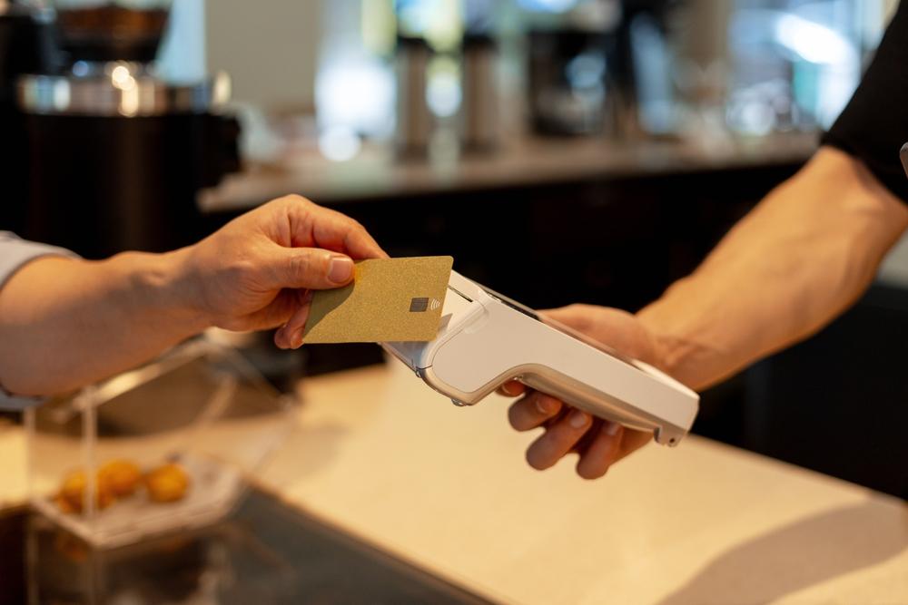 Cliente que paga con tarjeta en una terminal portátil en una cafetería