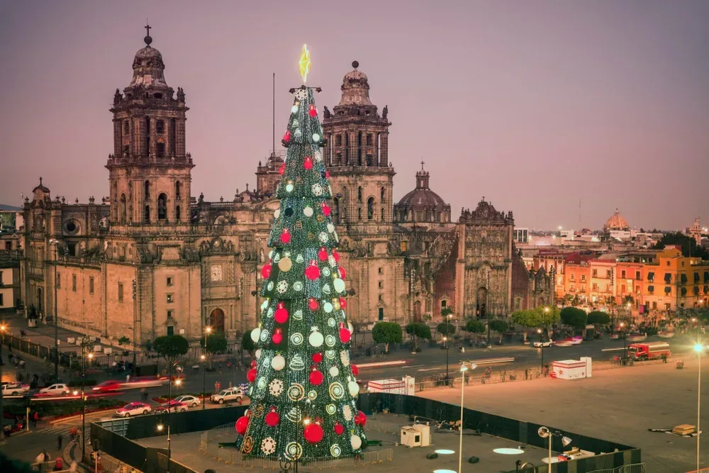 Árbol de Navidad iluminado en el Zócalo de la Ciudad de México frente a la Catedral Metropolitana al atardecer