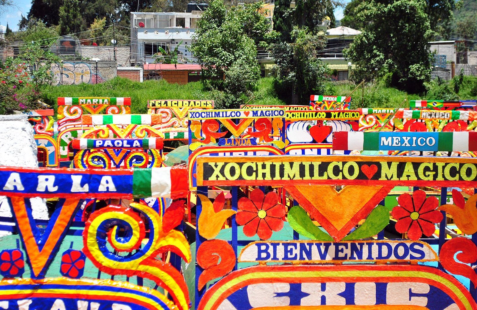 Trajineras coloridas con letreros de «Xochimilco mágico» y «Bienvenidos» en el embarcadero nuevo de Nativitas