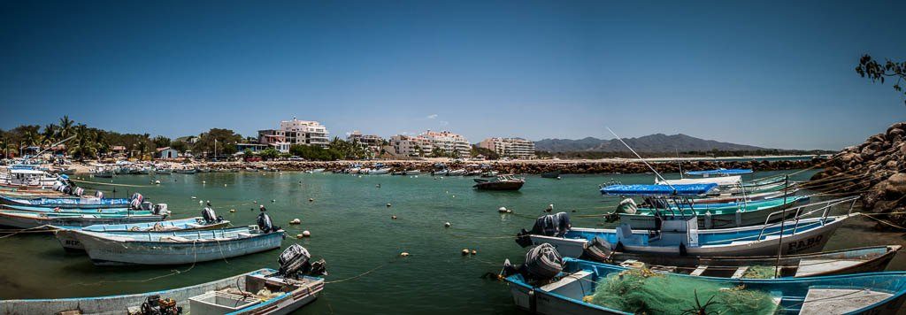 Lanchas de pesca amarradas en el puerto de Punta Mita, con edificios y cerros al fondo